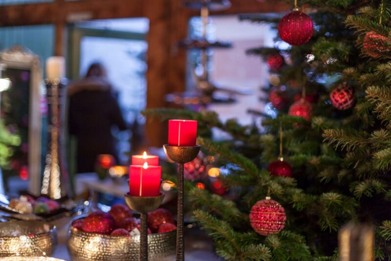 Weihnachtsbaum geschmückt im Verkaufsraum meine Tanne mit roten Kerzen in Kerzenständern und goldene Schalen mit Kugeln in glitzerndem Rot
