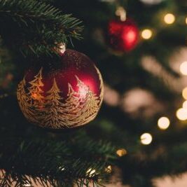 Christbaumkugel mit goldenem Ornament in Tannenbaumform an Weihnachtsbaum