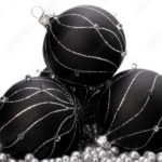 Schwarze Christbaumkugeln mit silbernen Ornamenten auf silbernen Perlen