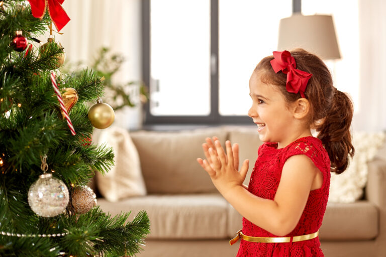 Mädchen freut sich über geschmückten Weihnachtsbaum