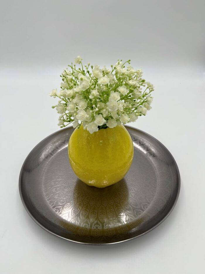 gelbe Vase in Zitronenform mit Schleierkraut und orientalischem Tablett