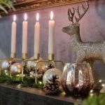 Weihnachtliche Deko auf einem Kamin mit Kerzen Windlicht und glitzerndem Hirsch